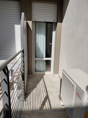 Un balcone con una porta scorrevole in vetro, un termosifone e una ringhiera in metallo.