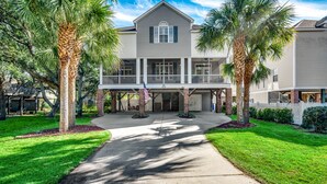 A two-story house with a front porch, palm trees, and a well-maintained lawn. - Shore Nuff: Surfside Beach. 1 blk to Beach, Private Pool, Golf Cart (Surfside Beach)
