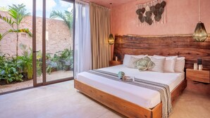 Ein Schlafzimmer mit einem großen Bett, einem hölzernen Kopfteil und Blick auf einen Garten durch eine Schiebetür.