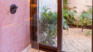 Ein modernes Badezimmer mit einer Glastür, die auf eine Terrassenfläche führt.