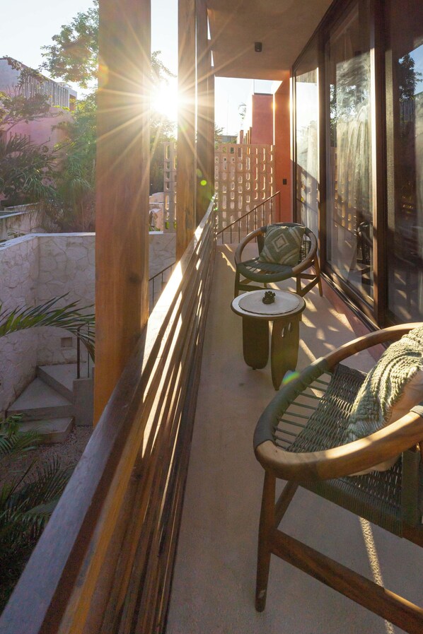 Un balcón con una silla, una mesa pequeña, barandilla y vistas al exterior.