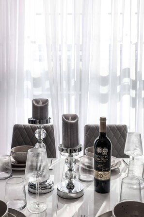 Een eettafel gedekt met kaarsen, een fles wijn en glazen.