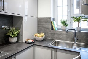 Een moderne keuken met een inbouwspoelbak, een fruitschaal en potplanten.