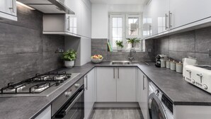 A modern kitchen with a gas stove, built-in oven, and a dishwasher. - Charming 4-Bedroom Apt Minutes from Borough St (Greater London)