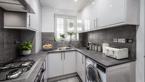 A modern kitchen with a gas stove, a dishwasher, and a built-in oven. - Charming 4-Bedroom Apt Minutes from Borough St (Greater London)