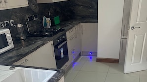 Une cuisine moderne avec des armoires blanches, un comptoir noir et une hotte de cuisinière en acier inoxydable.
