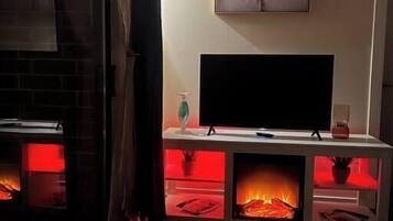 Uma sala de estar com lareira, televisão em um móvel e um quadro na parede.