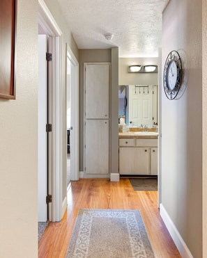 Enter a hallway leading to a kitchen area with a wooden floor and patterned rug.