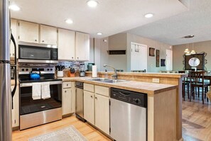 Enjoy cooking in this well-equipped kitchen with stainless steel appliances, a large island, and light cabinetry.