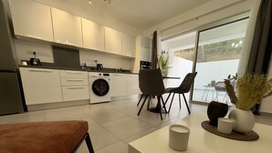 Een moderne keuken met witte kastjes, een wasmachine en een eethoek met een tafel en stoelen.