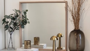 A marble fireplace with a mirror above it, a vase with dried branches, and decorative items on the mantel. - Appartement Montparnasse - rue de la Gaieté (Paris)