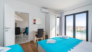 A hotel room with a bed, a desk, a chair, and a view of the city.
