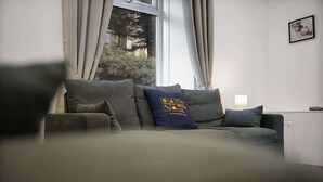 A living room with a sofa, a lamp, and a window with curtains.