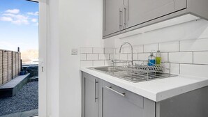 A kitchen with a sink, cabinets, and a dish rack.
