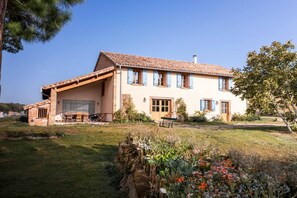 A two-story house with a sloped roof, a covered porch, and a garden with flowers and shrubs. - Getaway at La Métairie de Rouzies - Swimming pool (Tauriac)