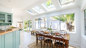 A bright kitchen with a dining area, skylights, and large windows.