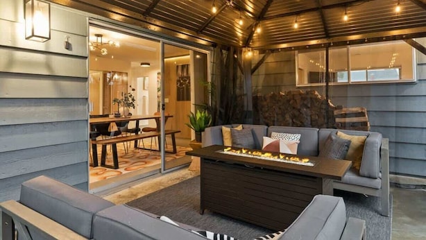 A cozy living area with a sofa, a coffee table, and a fireplace. - Chic Newberg Oasis: Mid-Century, Hot Tub, Fire Pits, Luxury Amenities (Newberg)