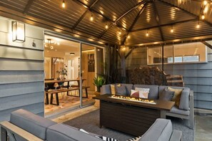 A cozy living area with a sofa, a coffee table, and a fireplace. - Chic Newberg Oasis: Mid-Century, Hot Tub, Fire Pits, Luxury Amenities (Newberg)