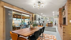 A modern kitchen with a wooden table, black chairs, and a unique patterned rug. - Chic Newberg Oasis: Mid-Century, Hot Tub, Fire Pits, Luxury Amenities (Newberg)