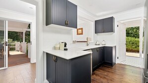 Una cocina moderna con armarios oscuros, encimera blanca y vistas al exterior.