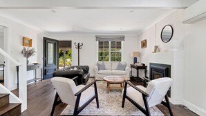 Una sala de estar con sofá, dos sillones, una mesita de centro, chimenea y un ventanal con vistas a zonas verdes.