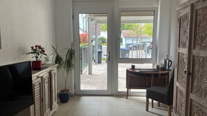 A modern living room with a flat-screen TV, a potted plant, and a sliding glass door leading to an outdoor area.