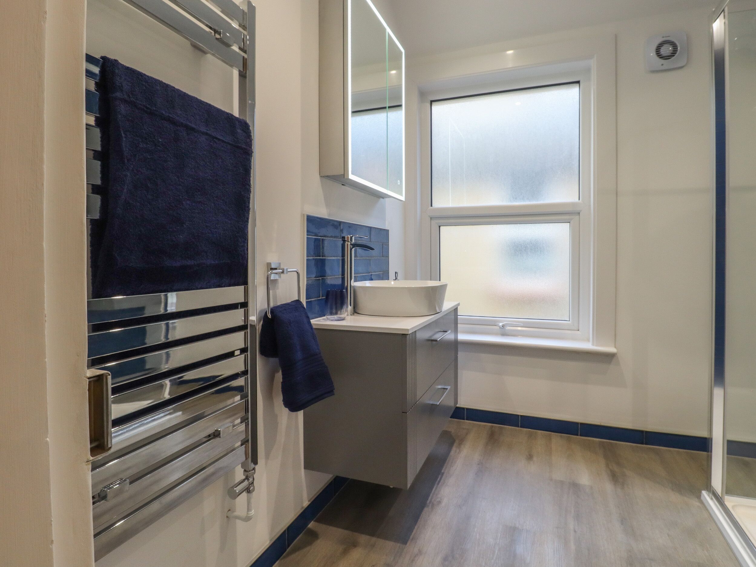 A modern bathroom with a glass shower enclosure, a built-in sink, and a towel rack.
