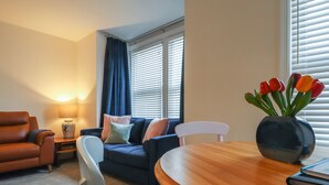 A living room with a sofa, armchairs, a coffee table, and a lamp. - Sally (Whitstable)