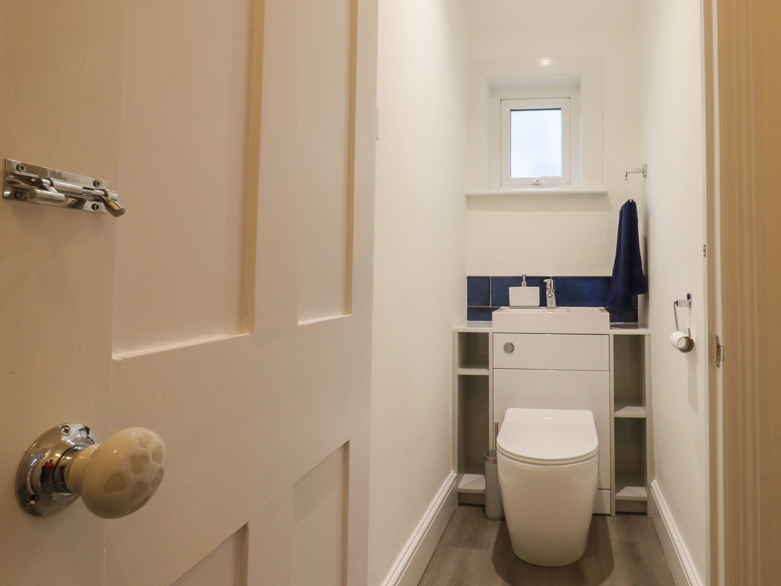 Un baño pequeño y estrecho con inodoro, lavamanos y ventana.