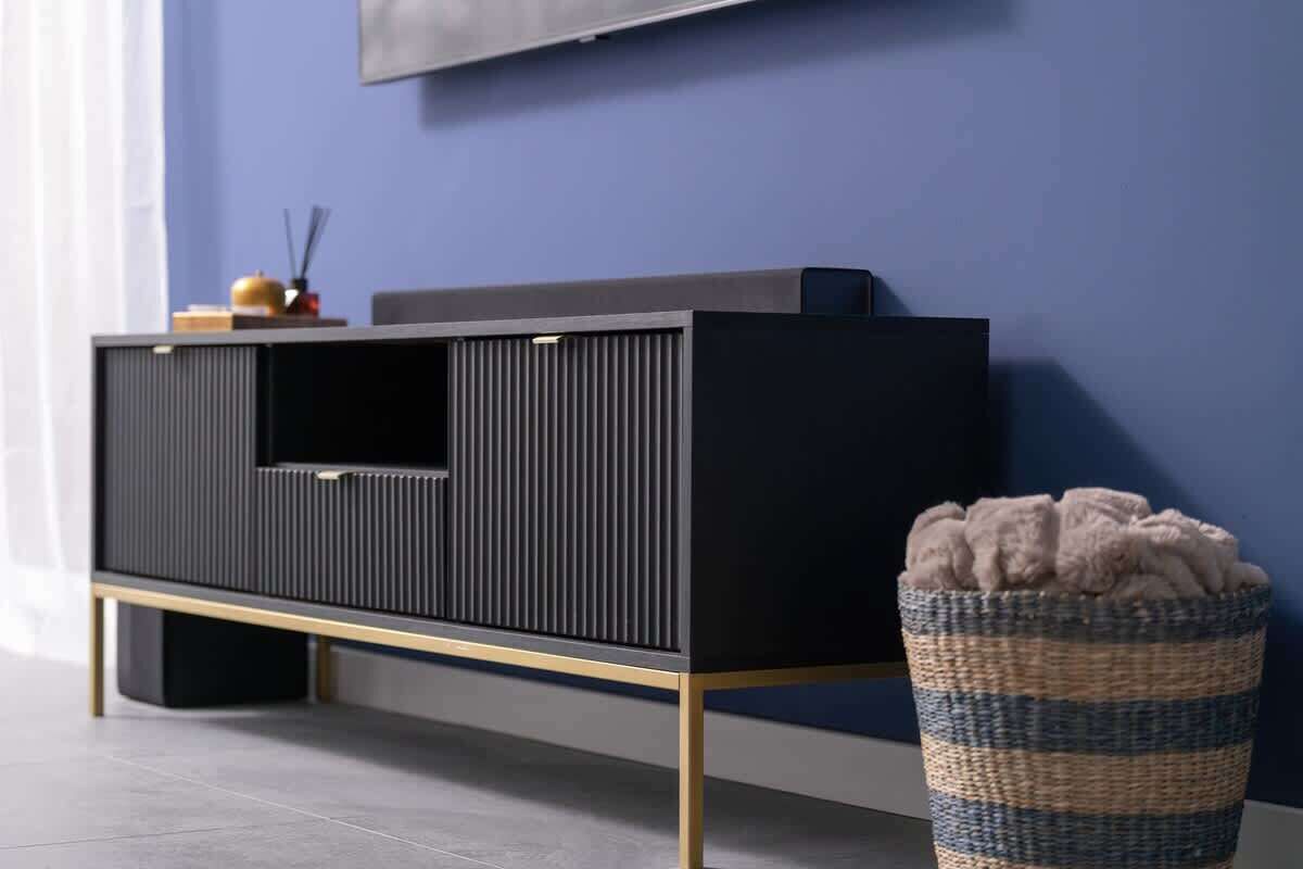 Un salon moderne avec un meuble de rangement pour appareils électroniques de couleur foncée, un téléviseur à écran plat fixé au mur et un panier en osier contenant un objet moelleux posé sur le sol.
