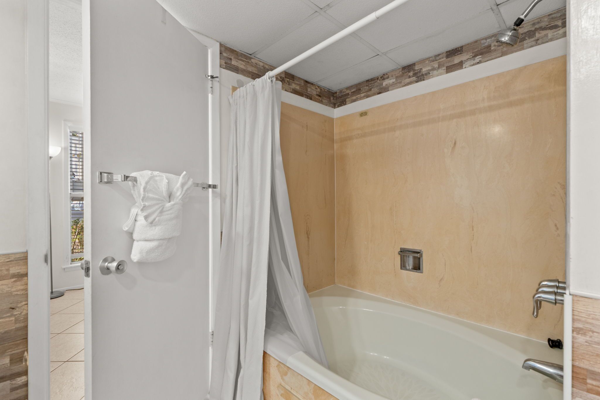 A bathroom with a bathtub, a shower curtain, and a towel rack.