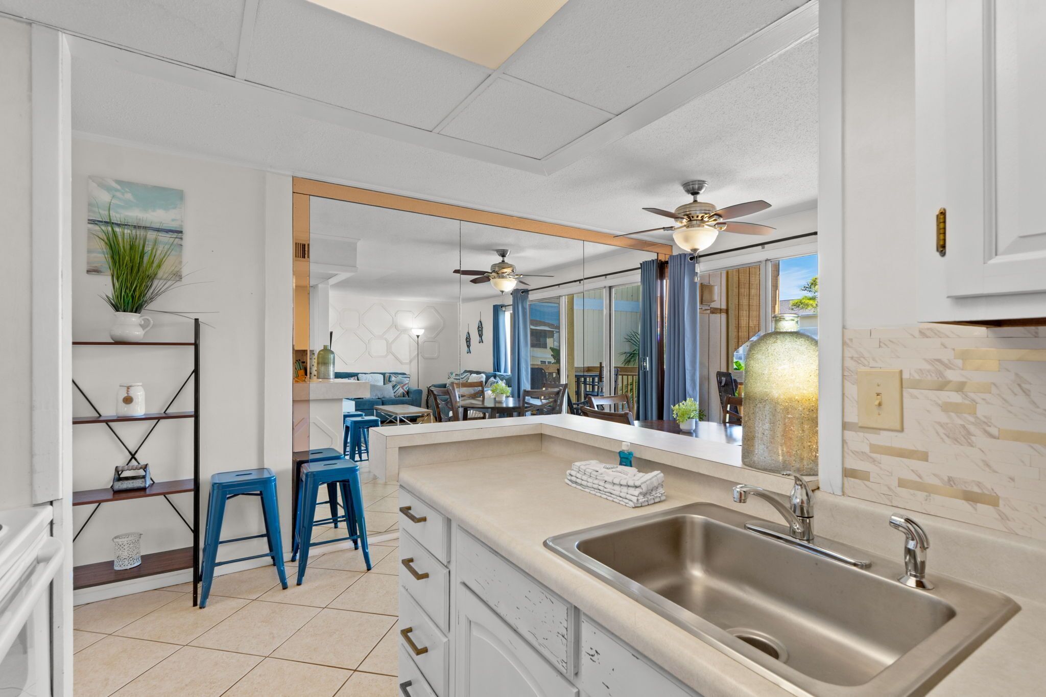 A modern kitchen with a large island, a double sink, and a ceiling fan.
