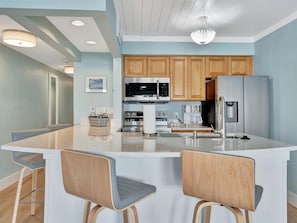 Cook your favorite meals in this bright, fully equipped kitchen with modern appliances and a spacious island for gathering. The coastal-inspired tones create a relaxed, airy atmosphere.