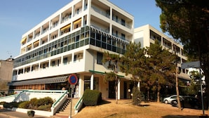 Un hotel de varios pisos con diseño moderno, que cuenta con balcones, una entrada cubierta y un área de estacionamiento.