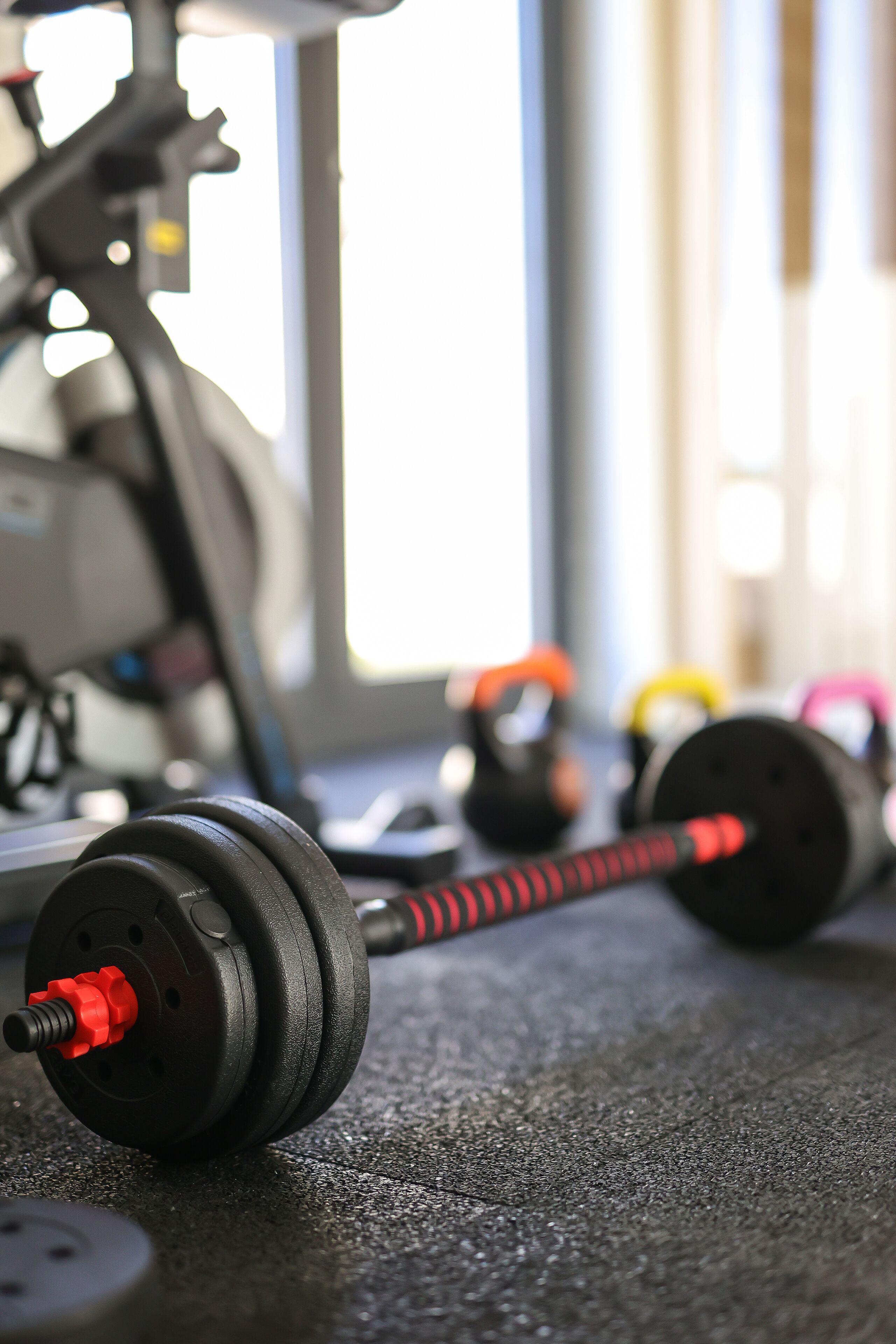 Un gimnasio con equipo de ejercicio, incluyendo mancuernas, balones de pesa y una bicicleta estática.