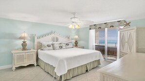 A bedroom with a bed, two bedside tables, a ceiling fan, and a view of the outdoors through a sliding door. - Beachfront 3BR, Pools, Hot Tubs, New to Rentals!! (Orange Beach)