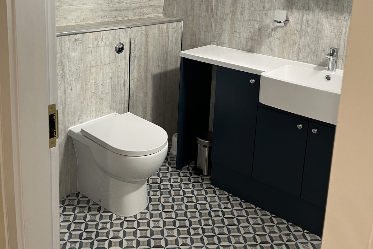 A modern bathroom with a skylight, a toilet, a sink, and dark cabinets.