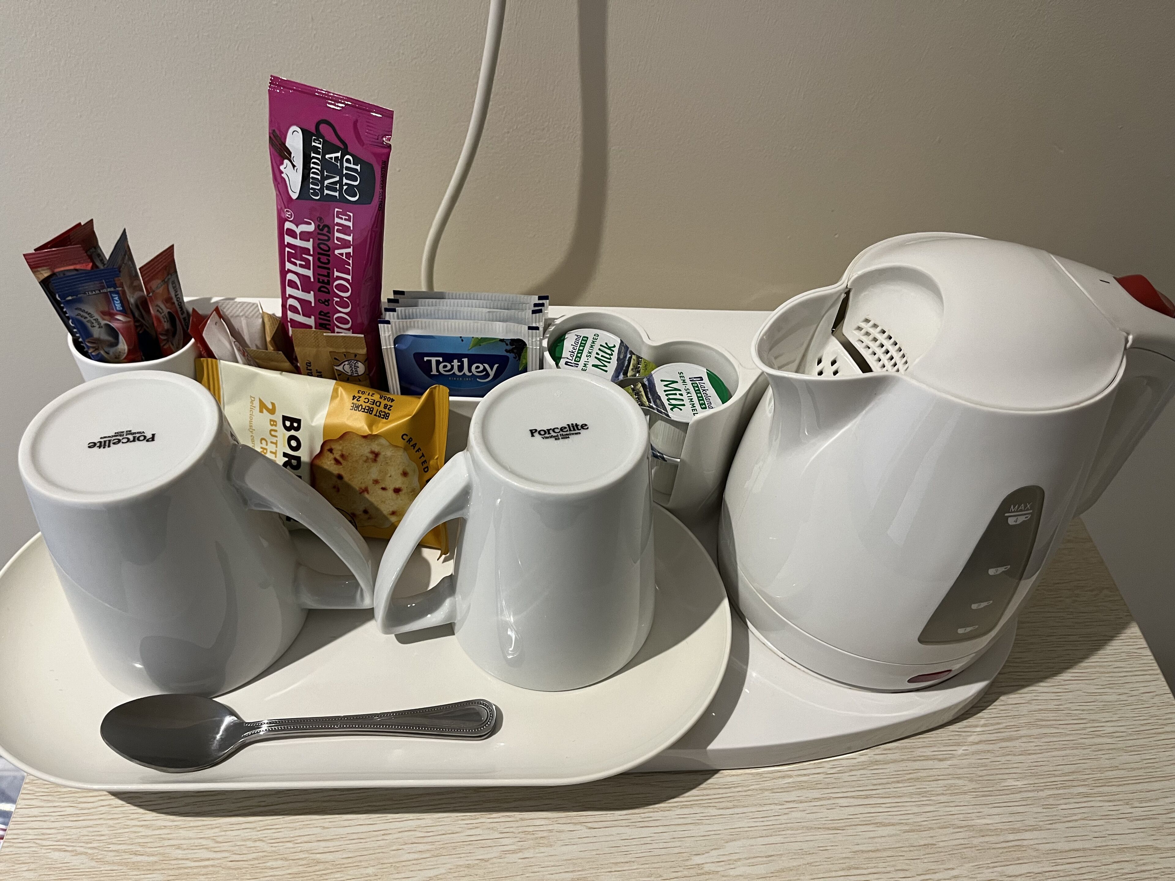 Una bandeja con tazas de café, una cuchara y varios pods y sobres de café.