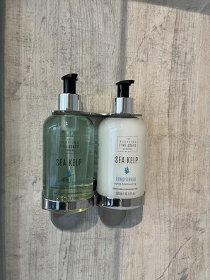 Two Sea Kelp products, a green hair and body shampoo and a white conditioner, on a wooden surface.