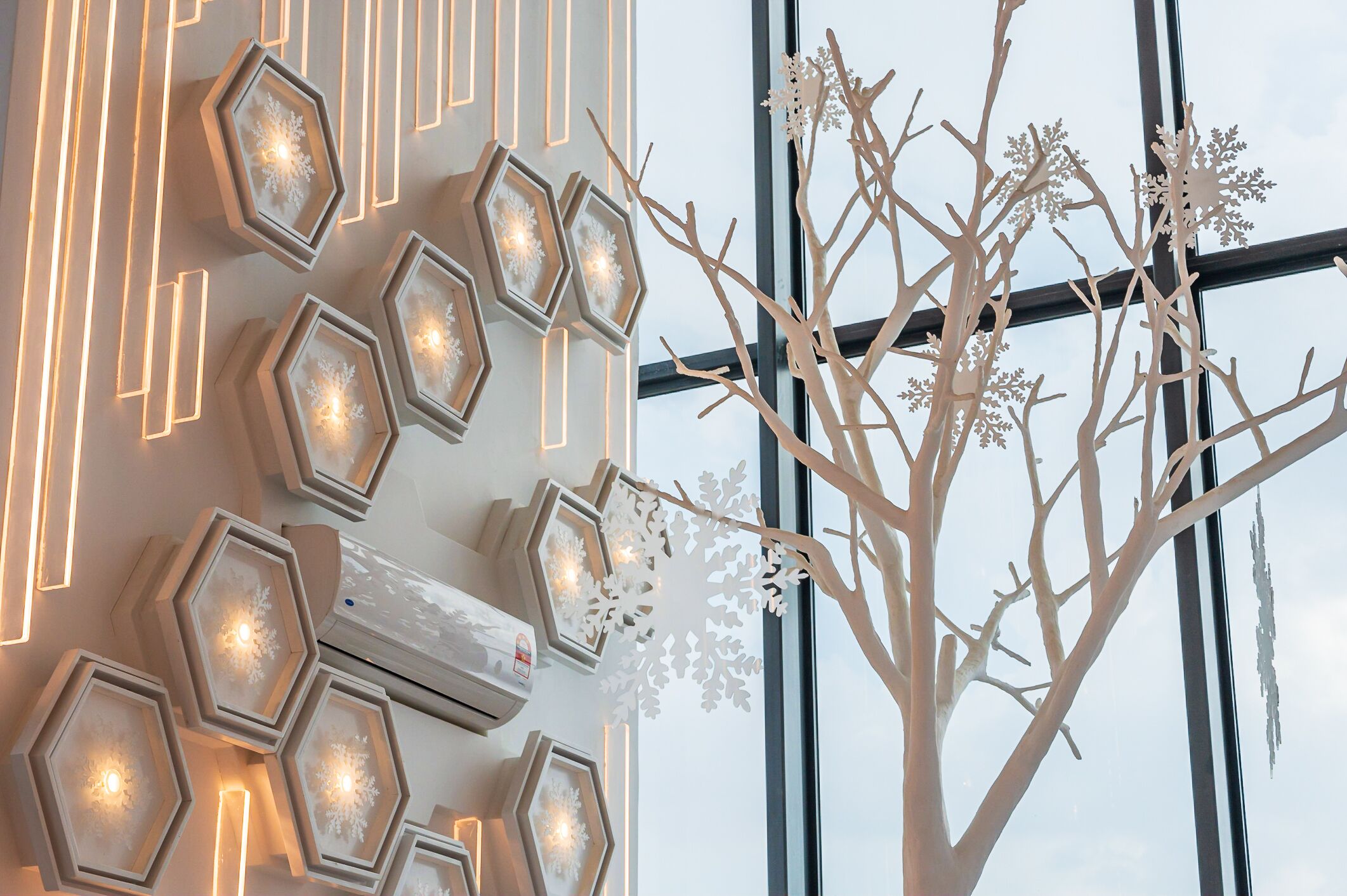 A modern interior with hexagonal light fixtures and a decorative tree with snowflakes.
