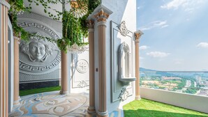 Un balcón con piso estampado, columnas y vista a un paisaje urbano.