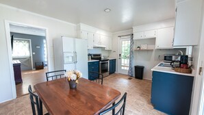 Una cocina moderna con armarios blancos, una mesa de comedor de madera y una pared azul de acento.