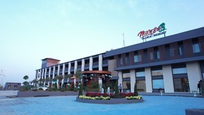 A modern hotel with a central courtyard, a covered seating area, and a sign reading "Maya Club & Resort". - Mansa Club And Resort (Ujjain)