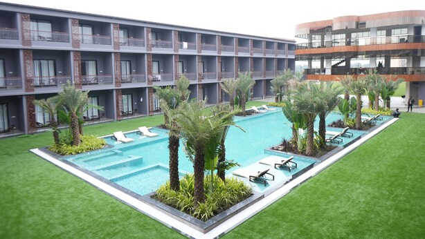A hotel with a swimming pool surrounded by palm trees and lounge chairs. - Mansa Club And Resort (Ujjain)