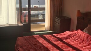 A hotel room with a bed, a dresser, a lamp, and a view of the city through a window. - Appt Résidence Maeva Mont d Arbois (Megève)