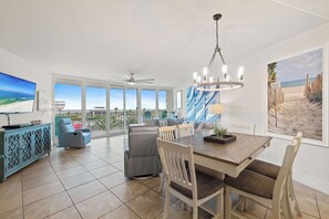 Uma sala de estar espaçosa com uma mesa de jantar, cadeiras, um sofá e uma TV.