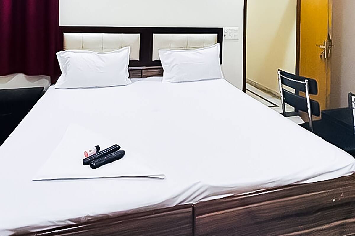 Een hotelkamer met een bed, een plafondventilator, een airconditioner, een kledingkast en een spiegel.