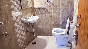 Ein Badezimmer mit einem weißen Waschbecken, einer Toilette und einer Duschkabine.