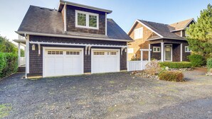 Une maison à deux étages avec un garage, une allée couverte et un jardin bien entretenu à l’avant.