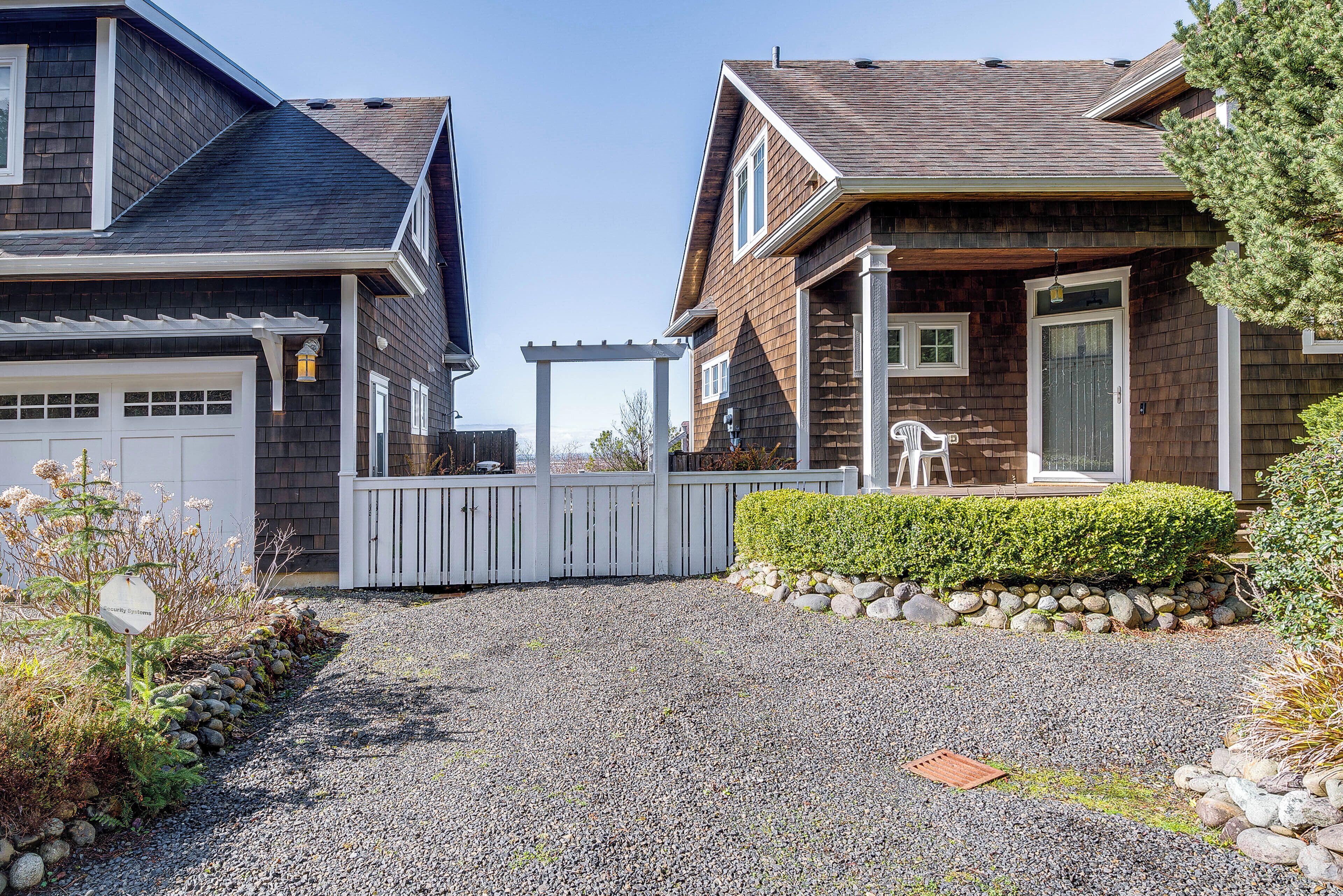 A residential driveway leading to a house with a garage, a wooden deck, and a well-maintained garden.